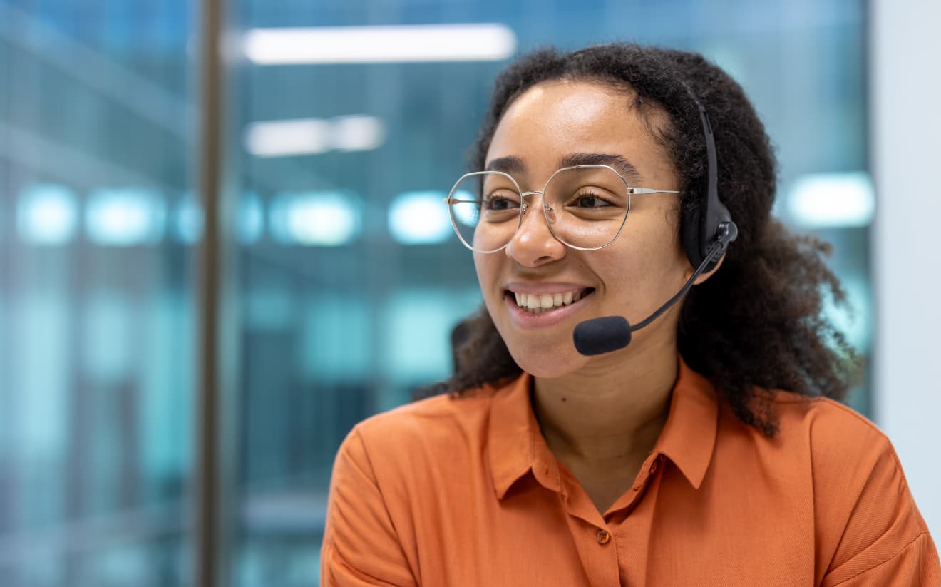 Smiling support agent with headset providing 24/7 phone assistance for B&B and inn operators.