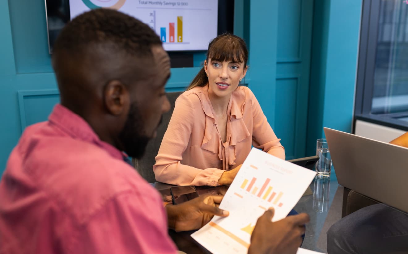 A team discussing revenue management strategies and reviewing charts with real-time data and market insights to adjust pricing for optimal profitability.