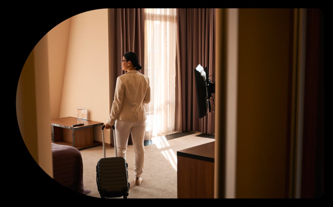 Woman looking into hotel room carrying a travel bag