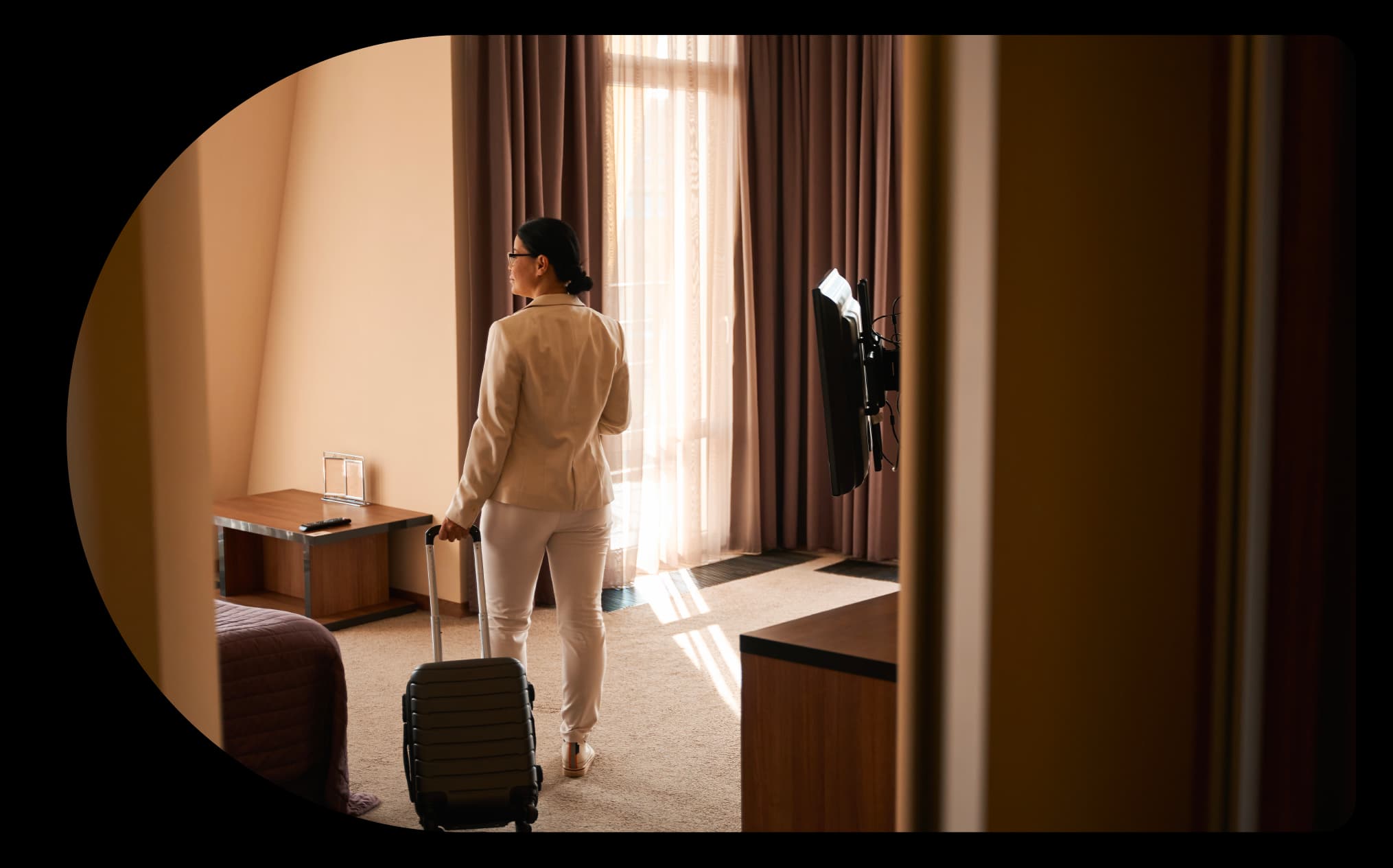Woman looking into hotel room carrying a travel bag