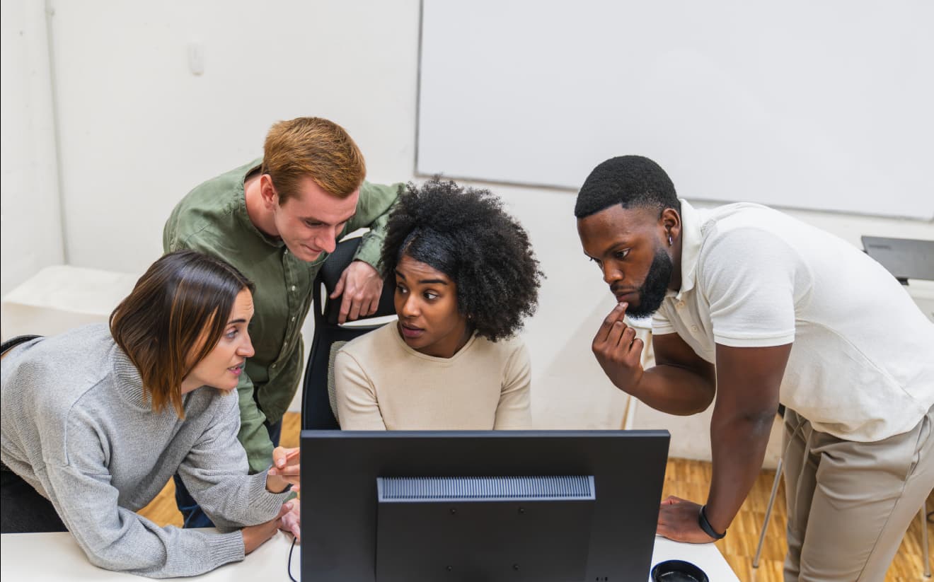 A group of professionals collaborating around a computer, discussing a digital strategy to improve booking potential and online presence for direct reservations.