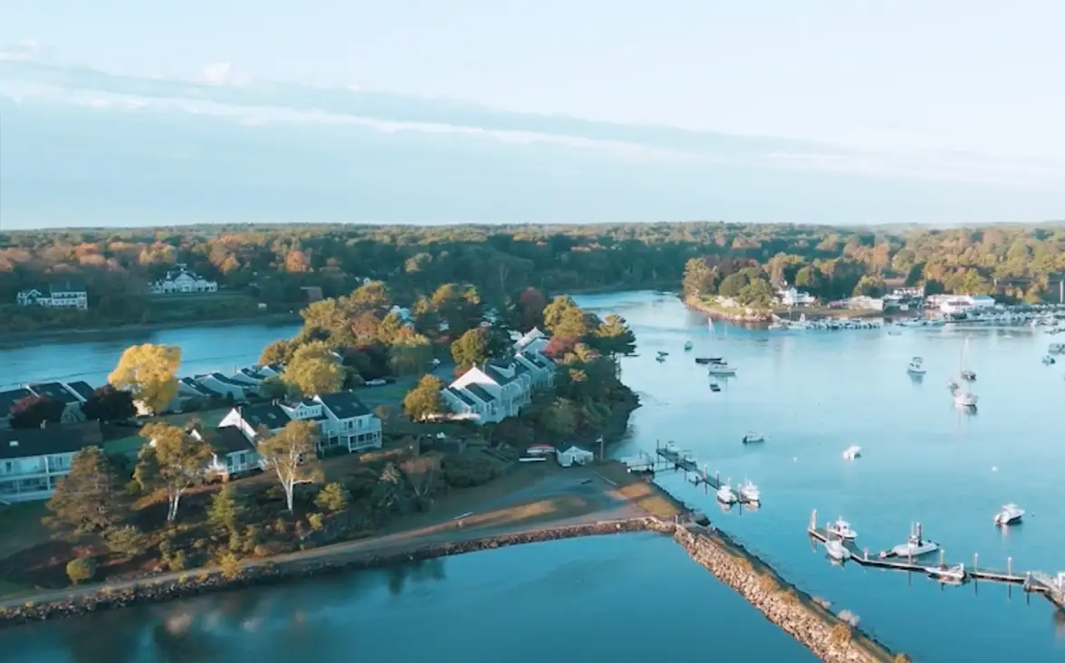 Aerial view of a tranquil coastal town with homes, docks, boats, and lush greenery.