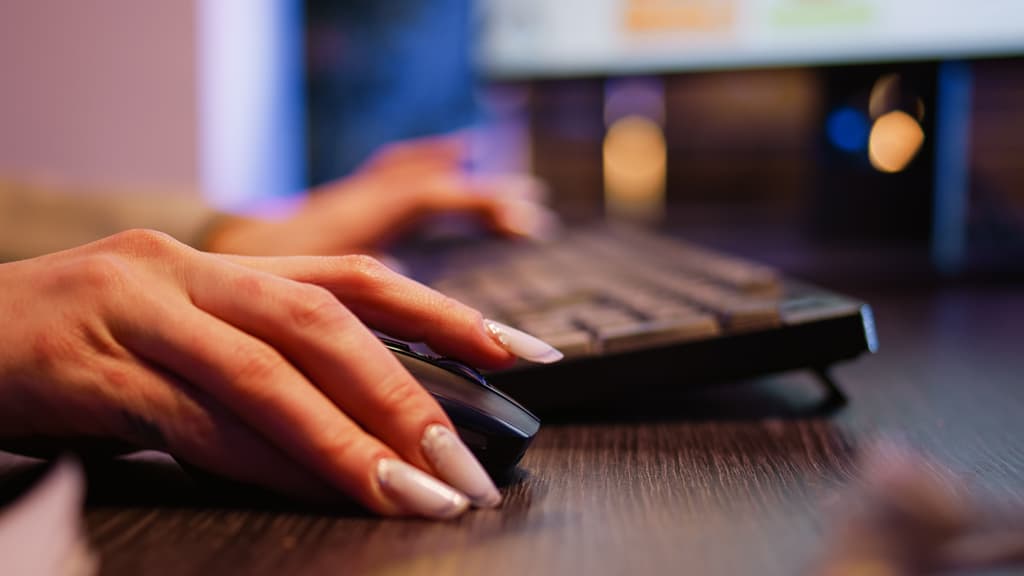 A female individual clicks and uses her computer mouse