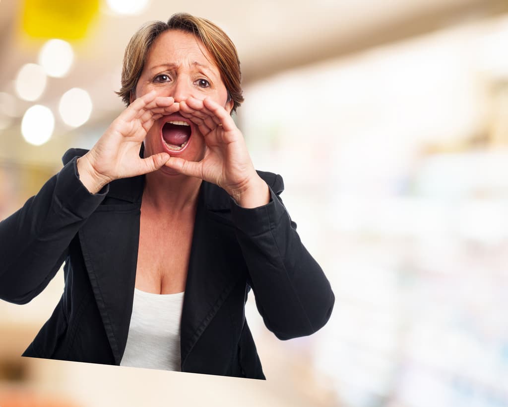 A frustrated business traveler in front of a property's front desk finds out she has no proper booking