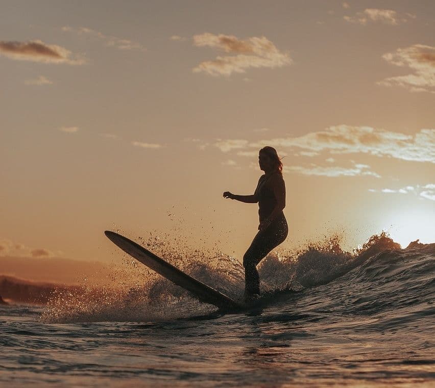 Girl riding a wave on top of a surf board