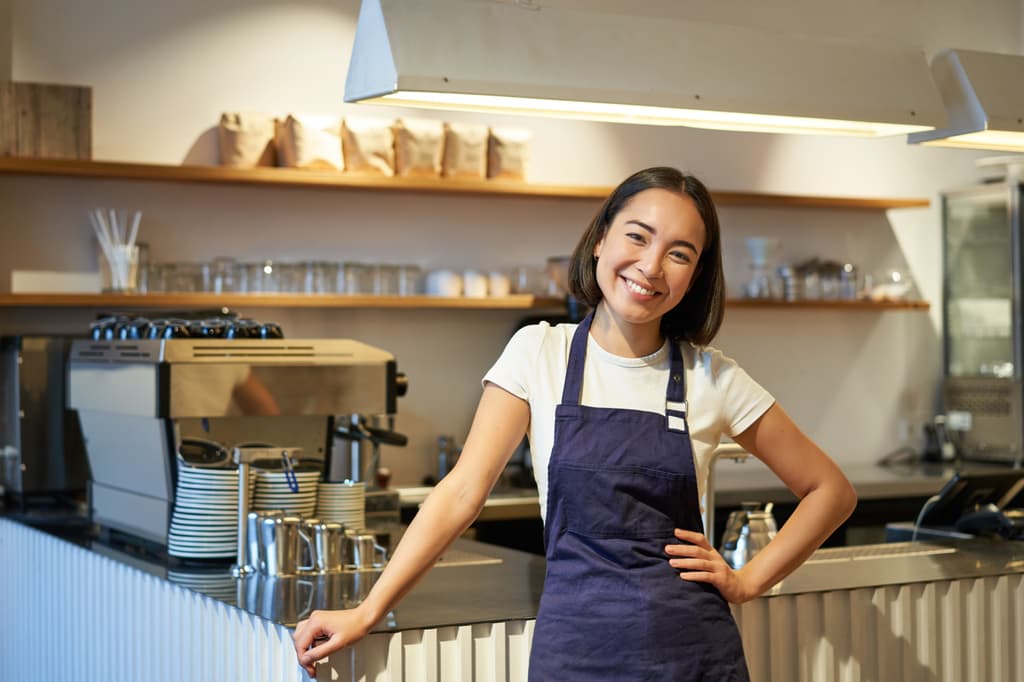 Female barista smiling in front of her coffee machine