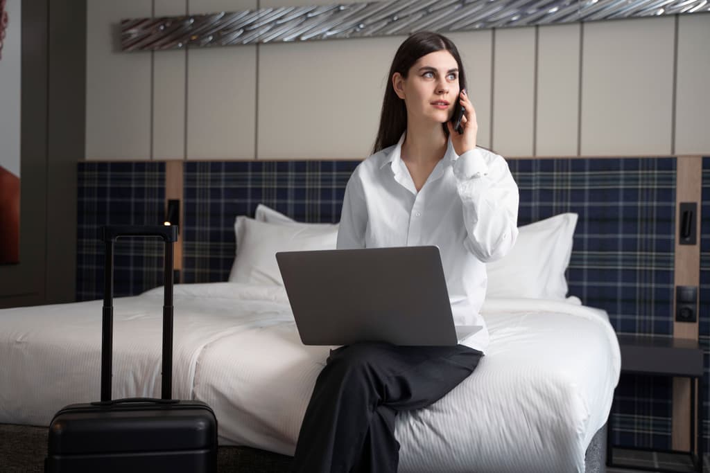 A property manager calls maintenance from a hotel room using her mobile phone