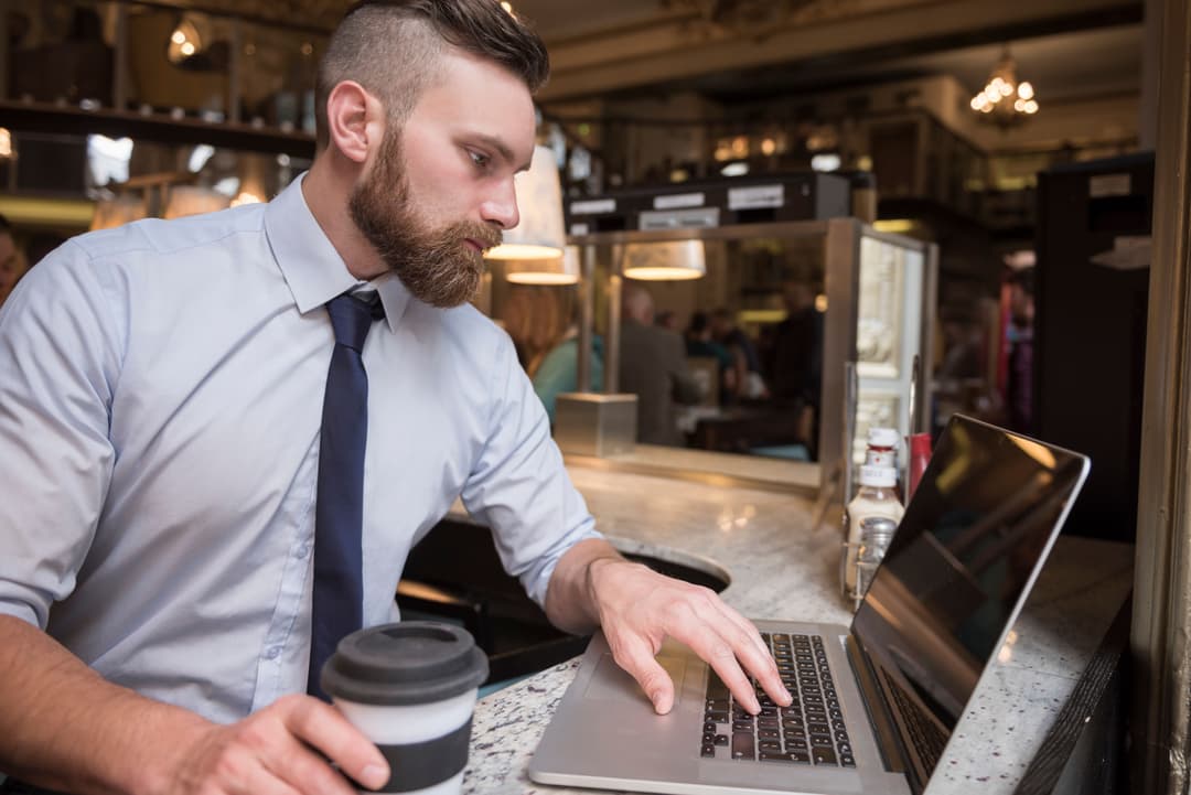 A boutique hotel owner checks his business analytics on his laptop.
