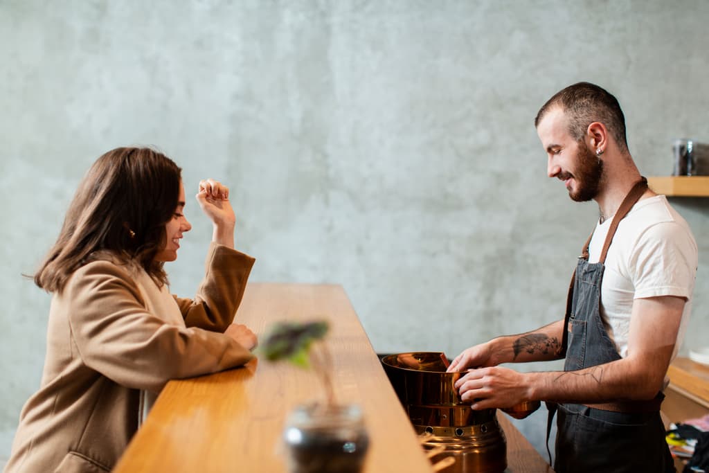Woman talking over the counter to a man serving coffee