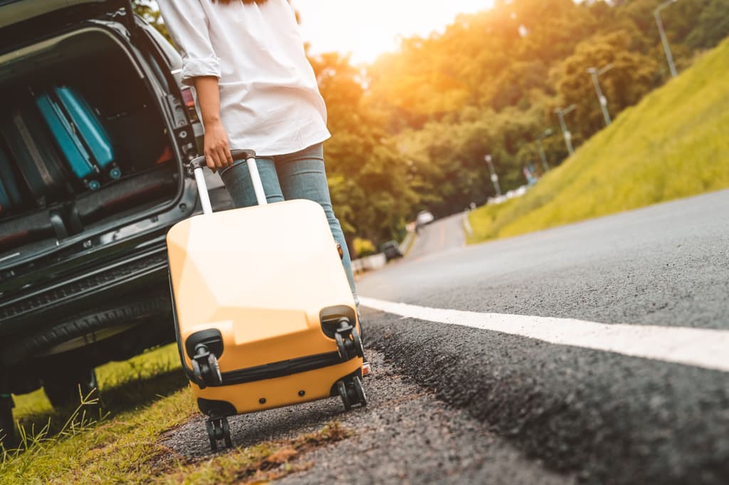 A female rider gets her luggage inside of the back of a car