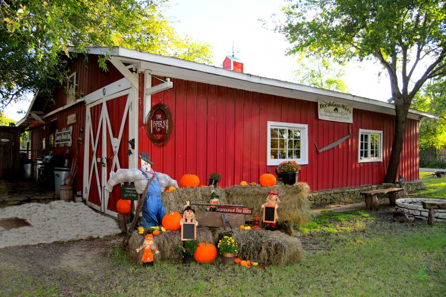 the red barn with a pumpkin and hay bale display