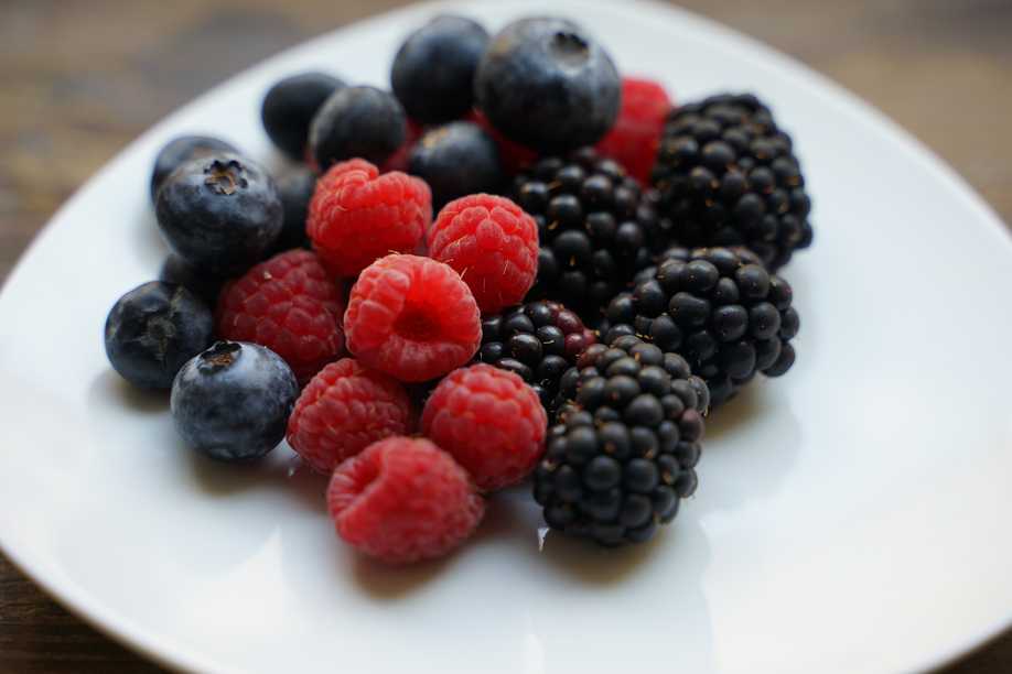 fresh blueberries raspberries and blackberries on white plate